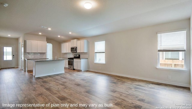 kitchen with light hardwood / wood-style flooring, white cabinets, an island with sink, and appliances with stainless steel finishes