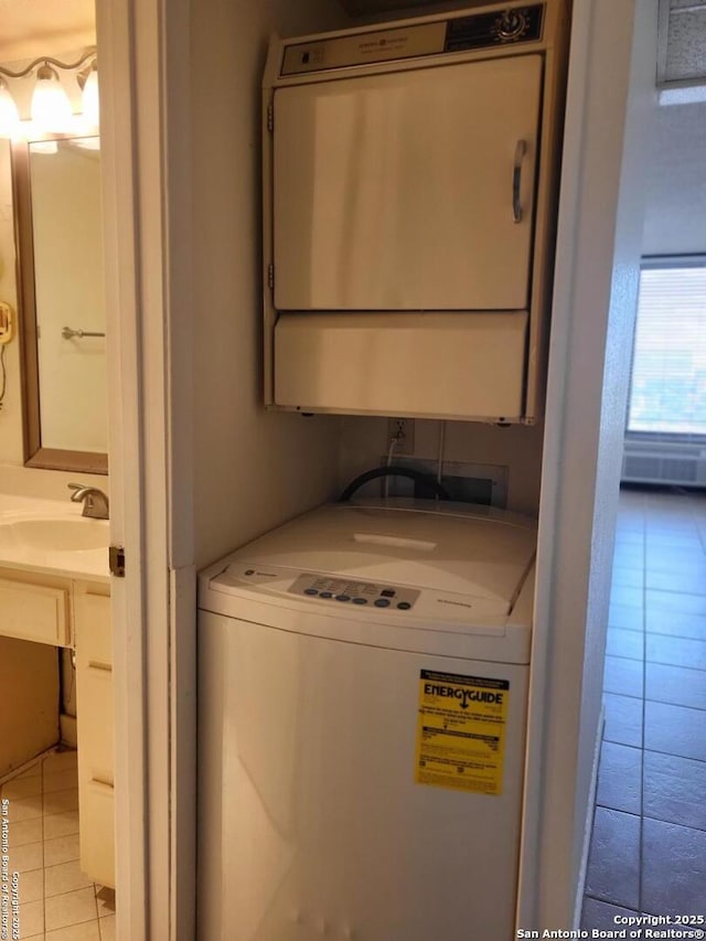 laundry area featuring sink, light tile patterned floors, and stacked washer / drying machine