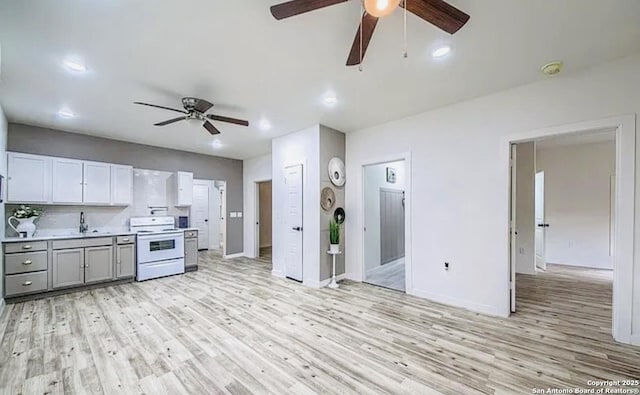 kitchen with light wood-type flooring, white cabinetry, white electric stove, and tasteful backsplash