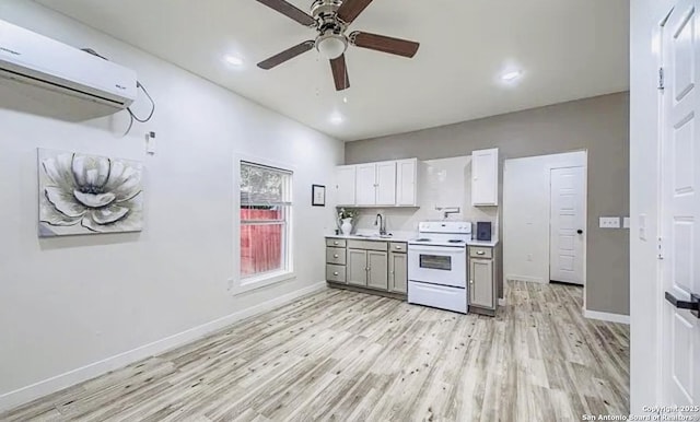 kitchen with white cabinets, an AC wall unit, sink, electric range, and light hardwood / wood-style floors