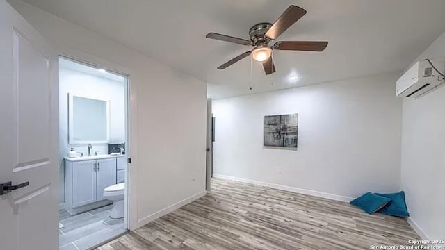 interior space with ceiling fan, light wood-type flooring, sink, and a wall unit AC