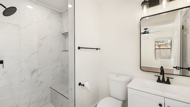 bathroom featuring ceiling fan, toilet, a tile shower, and vanity