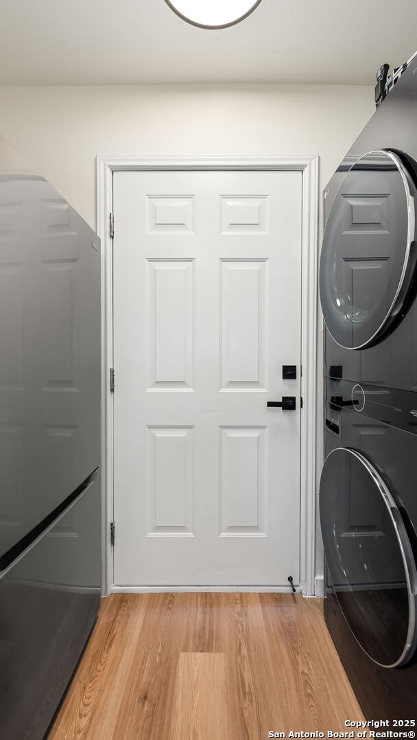 laundry room featuring light hardwood / wood-style floors and stacked washer and dryer