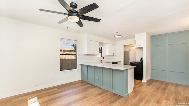 kitchen with kitchen peninsula, light stone countertops, tasteful backsplash, black electric range, and white cabinetry