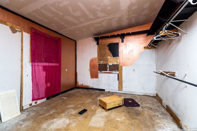 misc room with concrete flooring and wooden walls