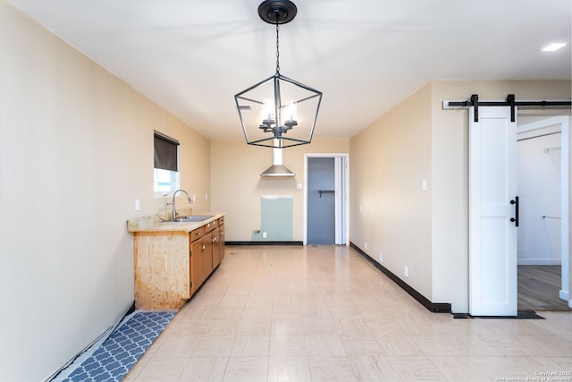 kitchen featuring pendant lighting, a barn door, sink, and a notable chandelier