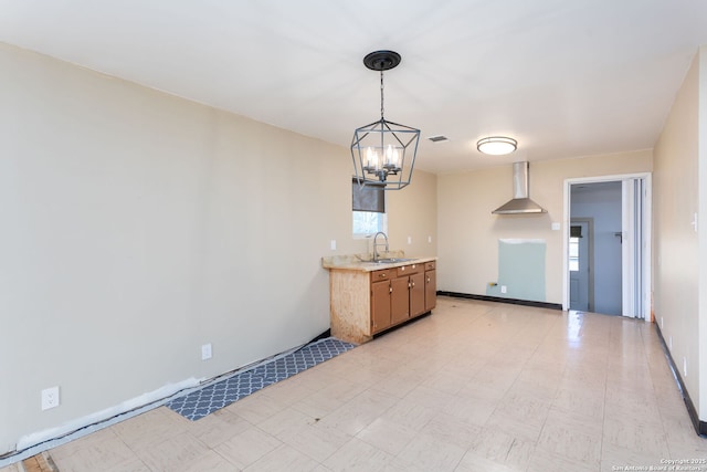 kitchen with sink, an inviting chandelier, plenty of natural light, decorative light fixtures, and wall chimney exhaust hood