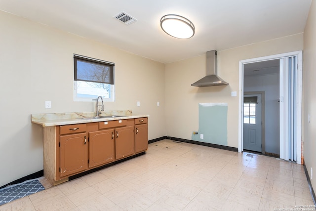 kitchen with wall chimney range hood and sink