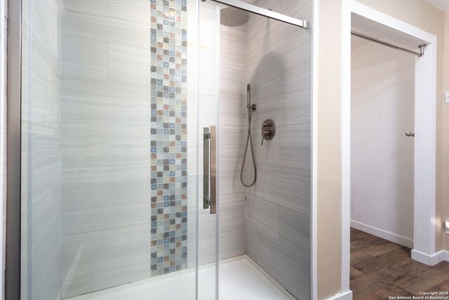 bathroom with an enclosed shower and wood-type flooring