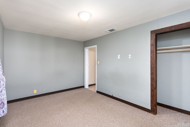 unfurnished bedroom with light colored carpet and a closet