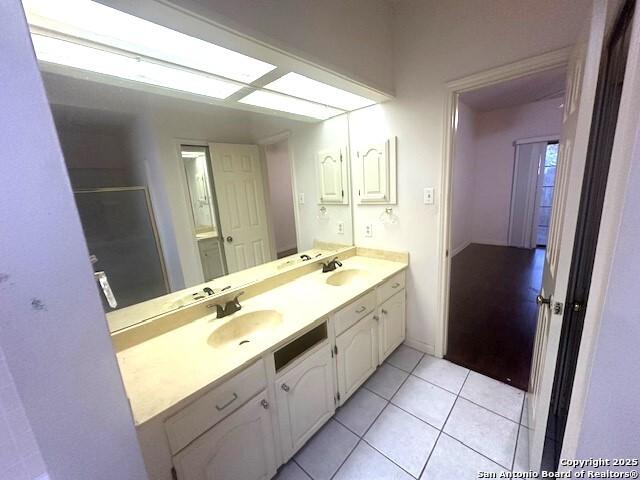 bathroom with tile patterned flooring, vanity, and a shower with door