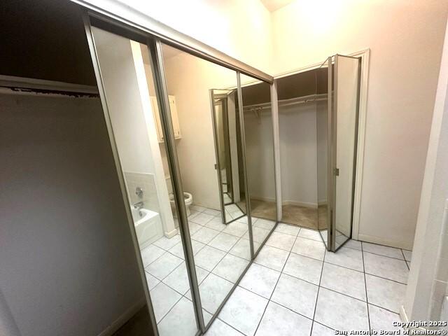 bathroom with tile patterned floors, a bath, and toilet