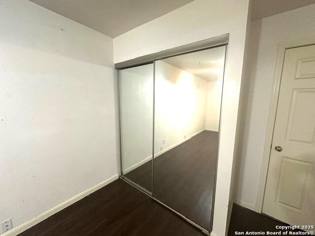 unfurnished bedroom with a closet and dark wood-type flooring