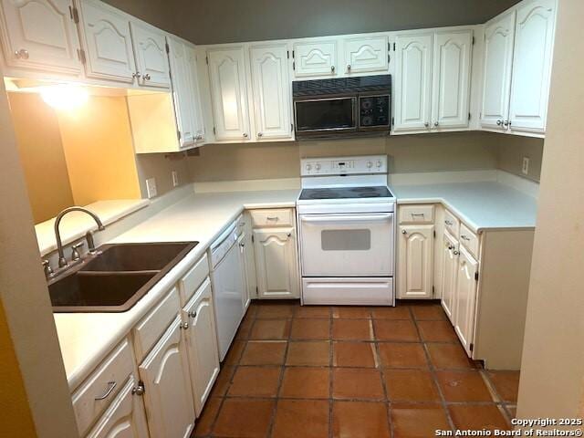 kitchen featuring white cabinets, white appliances, dark tile patterned floors, and sink