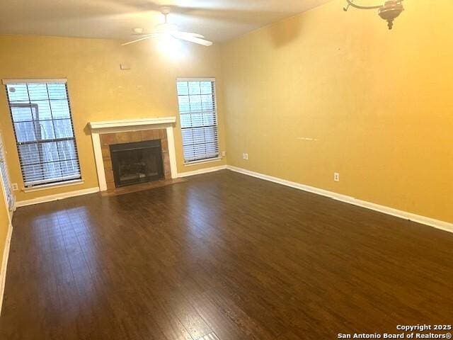 unfurnished living room featuring a wealth of natural light, a fireplace, ceiling fan, and dark hardwood / wood-style floors