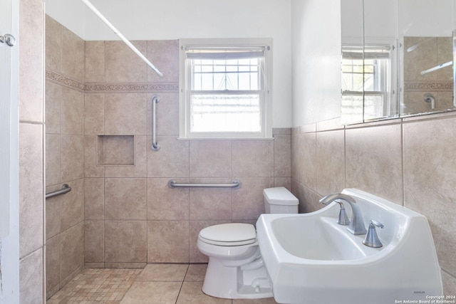 bathroom featuring tile patterned floors, sink, toilet, tile walls, and a tile shower