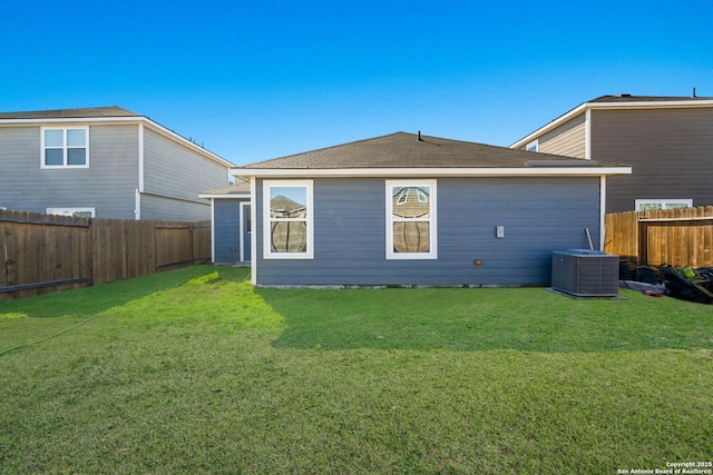 rear view of property featuring central AC unit and a lawn