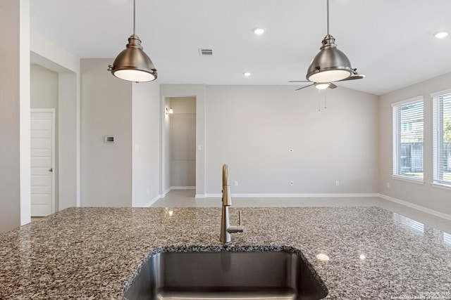 kitchen with stone counters, sink, and pendant lighting