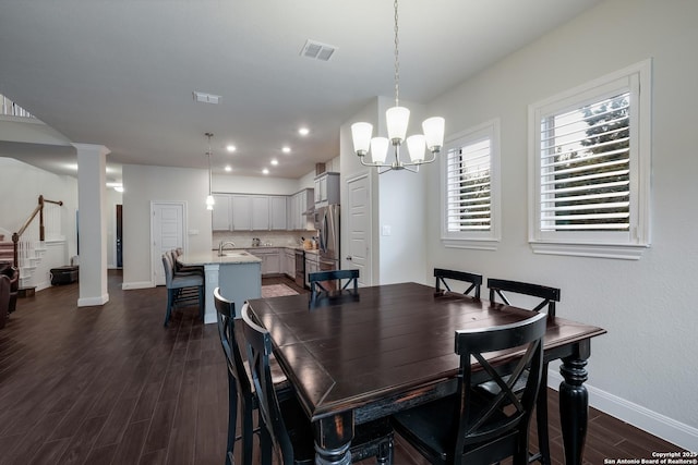 dining area featuring sink, dark wood-type flooring, and a notable chandelier