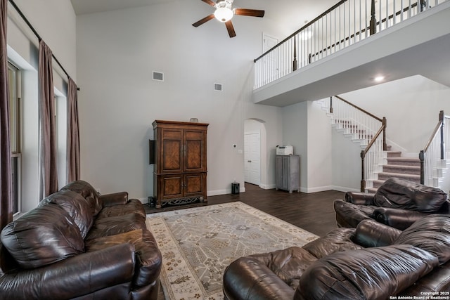 living room with ceiling fan, dark hardwood / wood-style flooring, and a towering ceiling