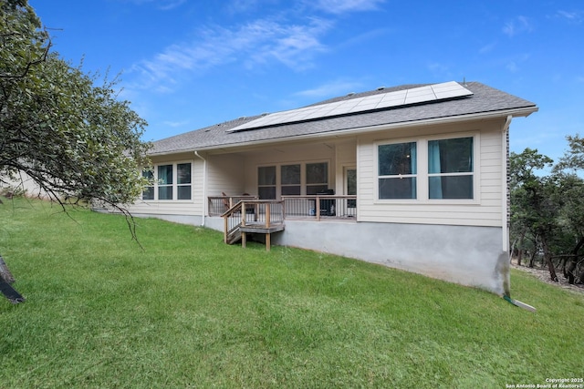 back of house with a lawn, a deck, and solar panels