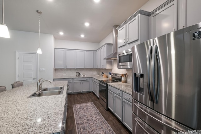 kitchen with light stone counters, sink, stainless steel appliances, and decorative light fixtures