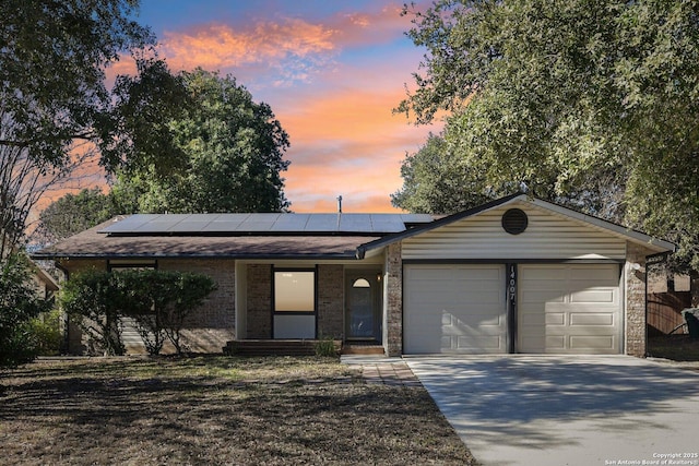 ranch-style home with a garage and solar panels