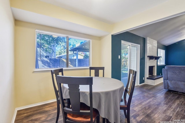 dining area with plenty of natural light, a fireplace, and dark hardwood / wood-style floors