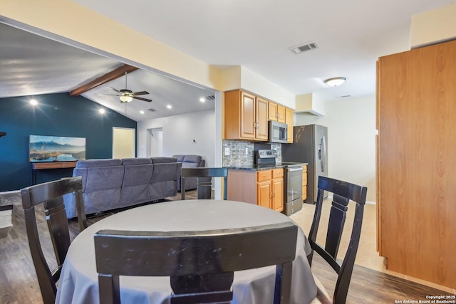 dining space featuring ceiling fan, lofted ceiling with beams, and hardwood / wood-style flooring