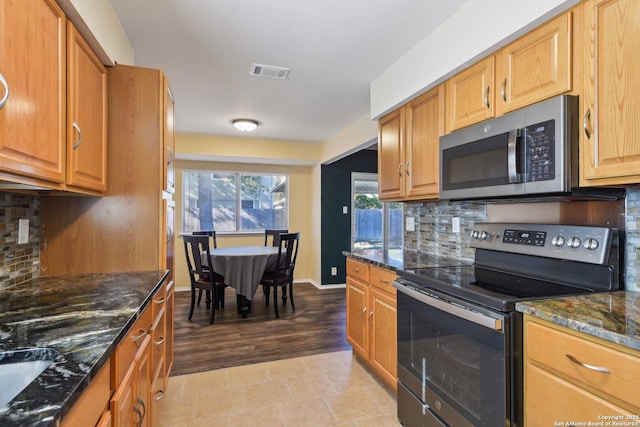 kitchen featuring tasteful backsplash, dark stone counters, and appliances with stainless steel finishes