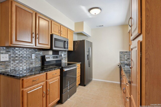 kitchen with stainless steel appliances, dark stone counters, and tasteful backsplash