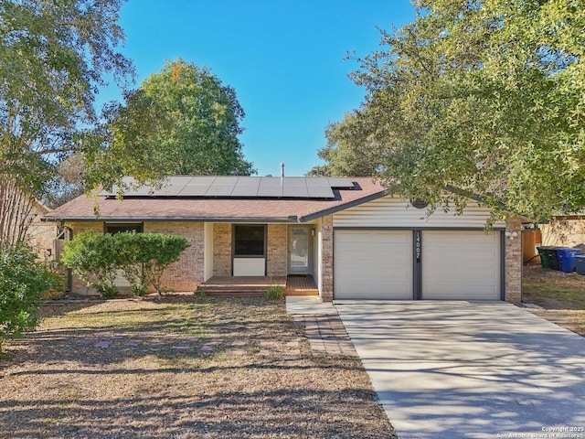 single story home with covered porch, solar panels, and a garage