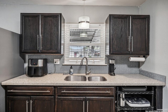 kitchen featuring pendant lighting, decorative backsplash, dark brown cabinets, and sink