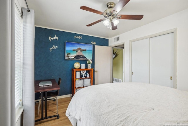 bedroom featuring multiple windows, wood-type flooring, a closet, and ceiling fan