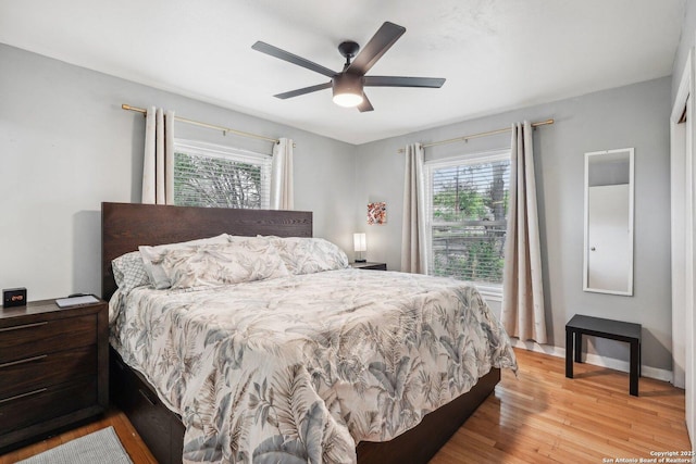 bedroom with multiple windows, ceiling fan, and light wood-type flooring