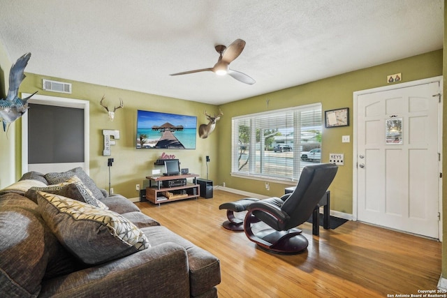 living room featuring ceiling fan, hardwood / wood-style floors, and a textured ceiling