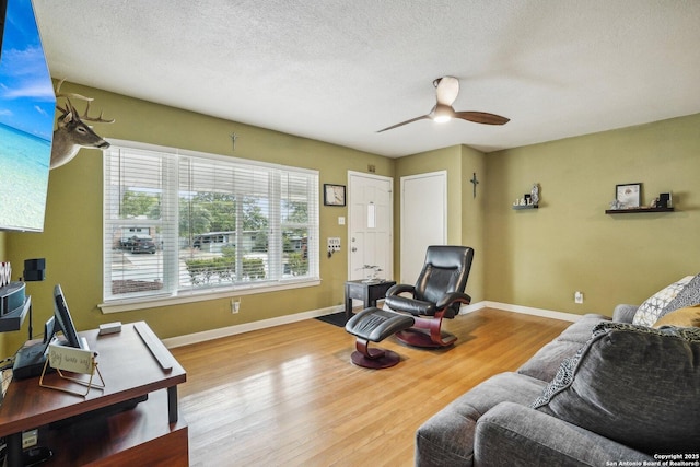 living room with ceiling fan, a textured ceiling, and light hardwood / wood-style flooring