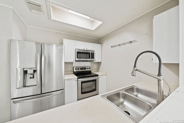 kitchen featuring a skylight, white cabinetry, sink, and appliances with stainless steel finishes