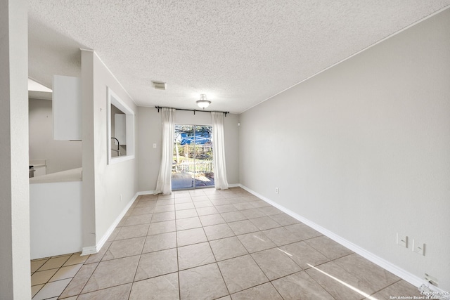 empty room featuring light tile patterned flooring and a textured ceiling