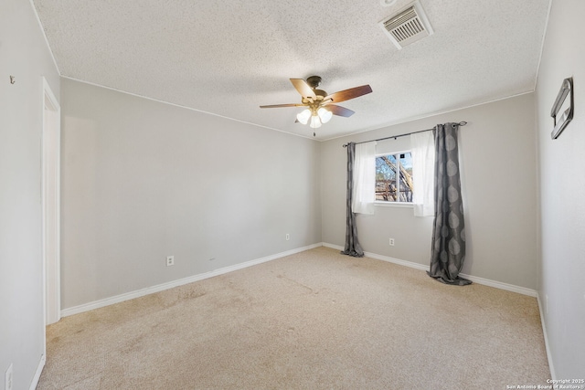 empty room featuring ceiling fan, light colored carpet, and a textured ceiling