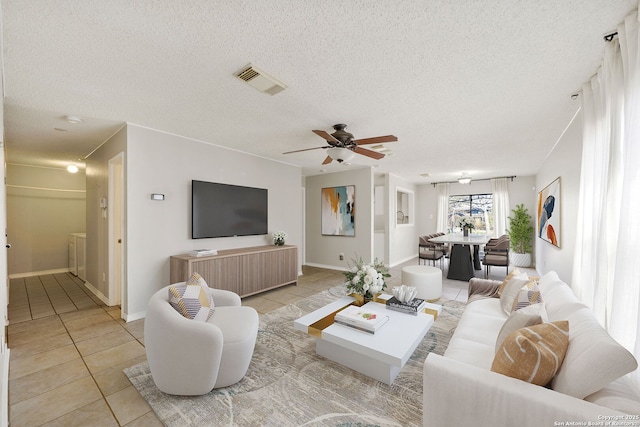 living room featuring ceiling fan, light tile patterned floors, and a textured ceiling