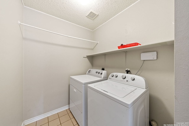 laundry area featuring independent washer and dryer, a textured ceiling, and light tile patterned flooring