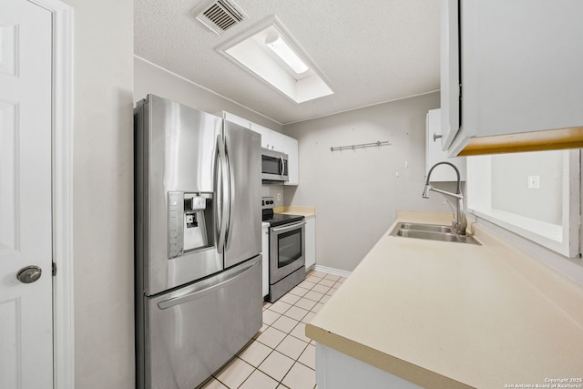 kitchen featuring white cabinets, sink, light tile patterned floors, and stainless steel appliances