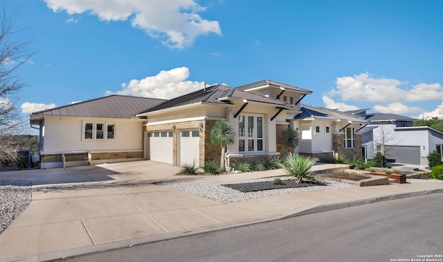 prairie-style home featuring a garage, stone siding, metal roof, and stucco siding