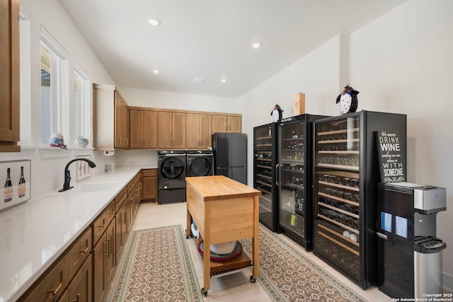 kitchen with beverage cooler, butcher block countertops, freestanding refrigerator, independent washer and dryer, and a sink