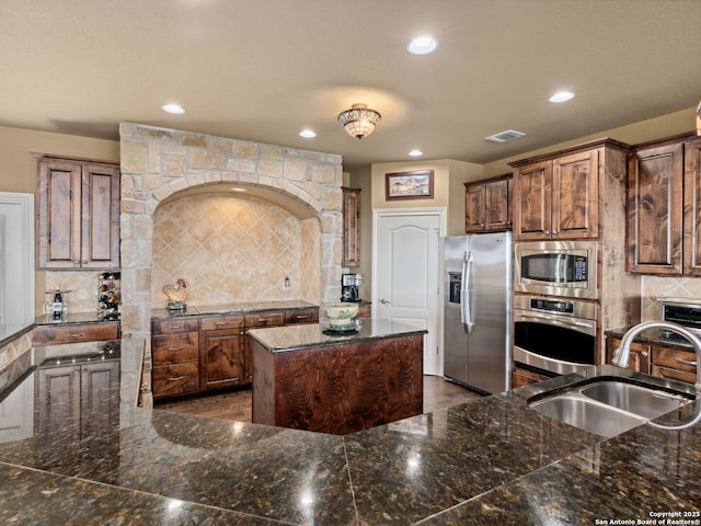 kitchen with decorative backsplash, a center island, stainless steel appliances, and sink