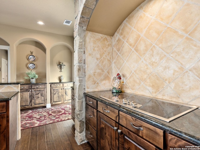 kitchen with black electric cooktop, dark hardwood / wood-style flooring, and dark stone countertops