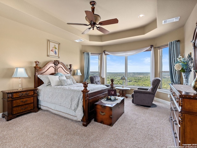 bedroom featuring ceiling fan, light carpet, and a tray ceiling