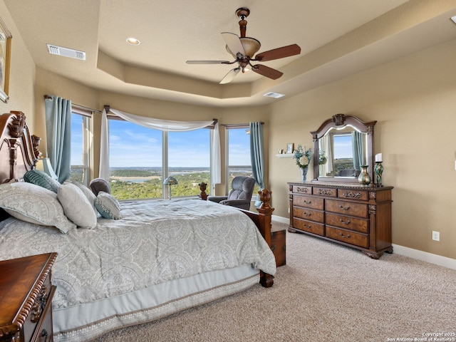 carpeted bedroom with ceiling fan and a tray ceiling