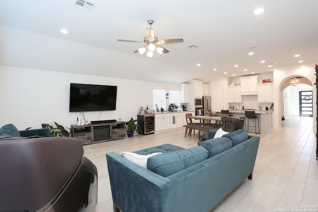 living room featuring ceiling fan, light hardwood / wood-style flooring, beverage cooler, and vaulted ceiling